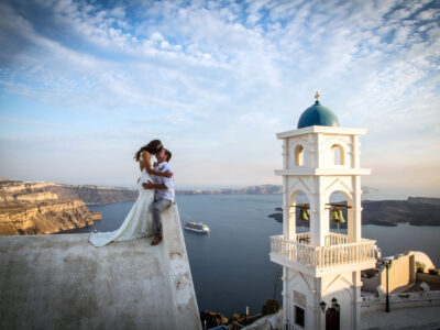 couple kissing at the rooftop of a church with a spectacular view of Santorini island caldera